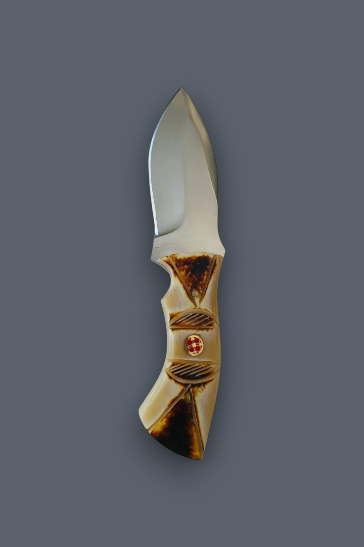 A pocket knife with a polished silver steel blade and a decorative handle made of carved bone or horn in warm beige and brown tones, featuring a small red circular accent, shown against a solid dark gray background.