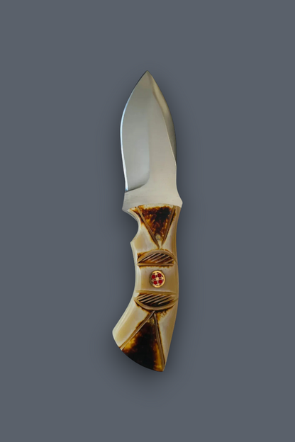A pocket knife with a polished silver steel blade and a decorative handle made of carved bone or horn in warm beige and brown tones, featuring a small red circular accent, shown against a solid dark gray background.