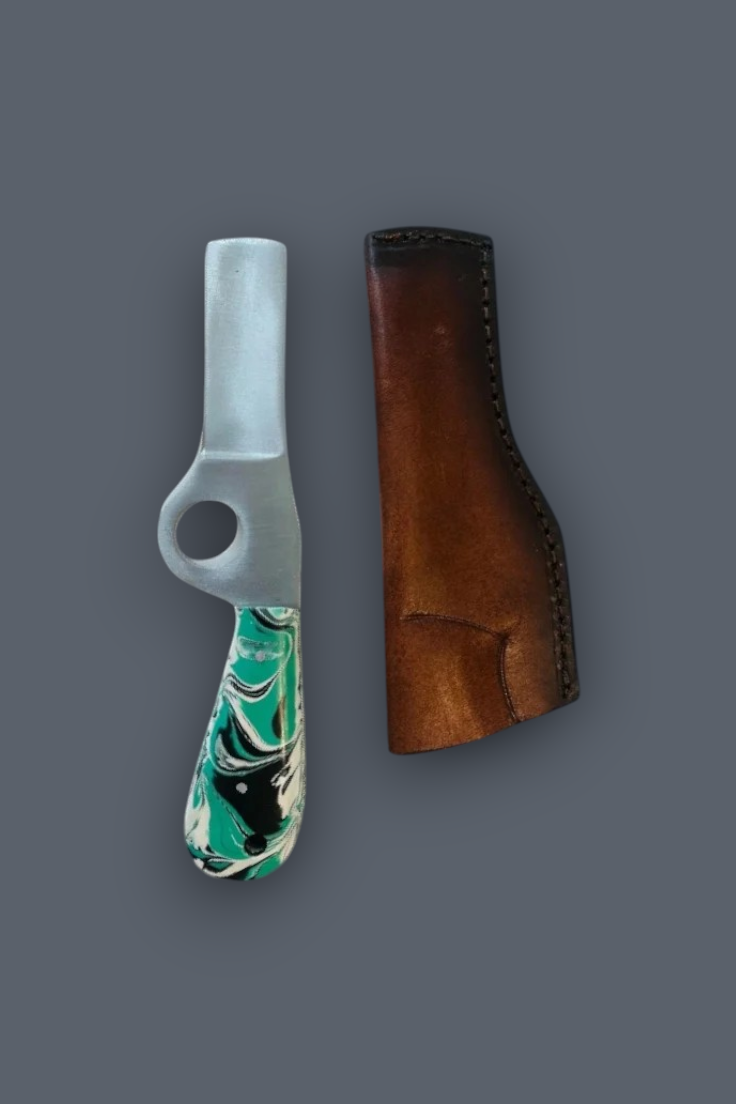 A small hand tool with a silver metal head and a marbled green, black, and white handle, shown next to a brown leather sheath on a dark gray background.