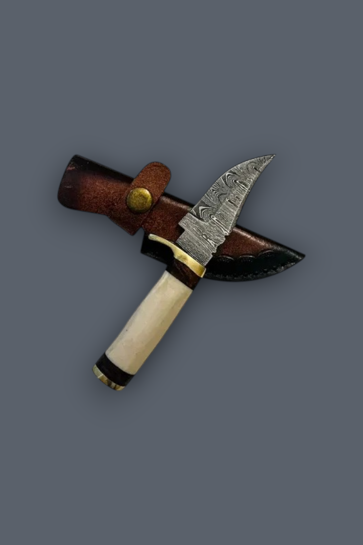 A fixed-blade knife with a patterned steel blade, cream-colored handle, and brown leather sheath, displayed diagonally on a solid dark gray background.