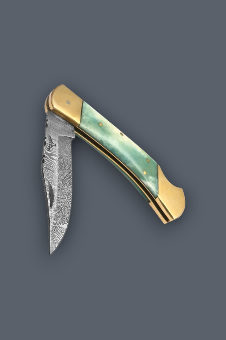 A folding pocket knife with a Damascus steel blade, gold-toned brass bolsters, and a green mother-of-pearl handle scale, shown against a solid dark gray background.