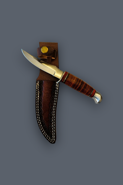 A fixed-blade knife with a silver blade, brass bolster, and striped brown wooden handle, shown partially inserted into a brown leather sheath with white stitching against a solid dark gray background.