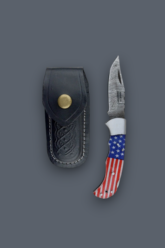 A compact folding pocket knife with sheath with a red, white, and blue American flag pattern handle, shown next to its black leather sheath with a brass snap button, on a solid dark gray background.