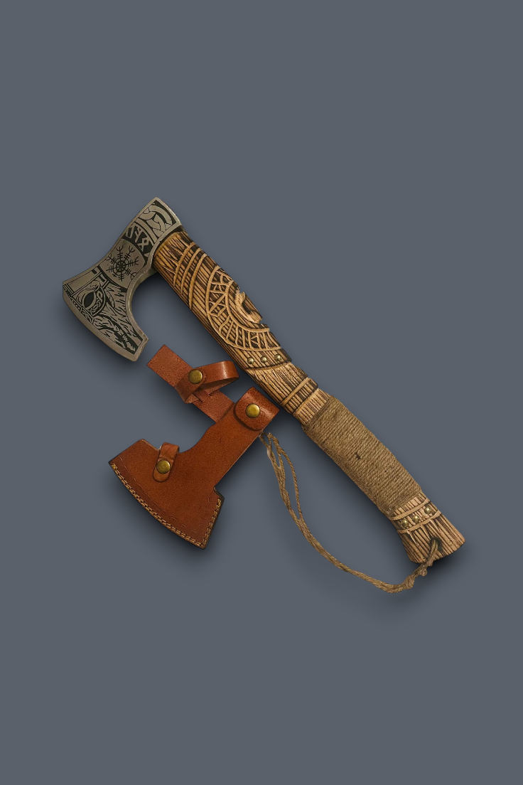 A Viking-style bearded axe with a carved wooden handle and engraved steel head, shown alongside a brown leather sheath on a solid dark gray background.