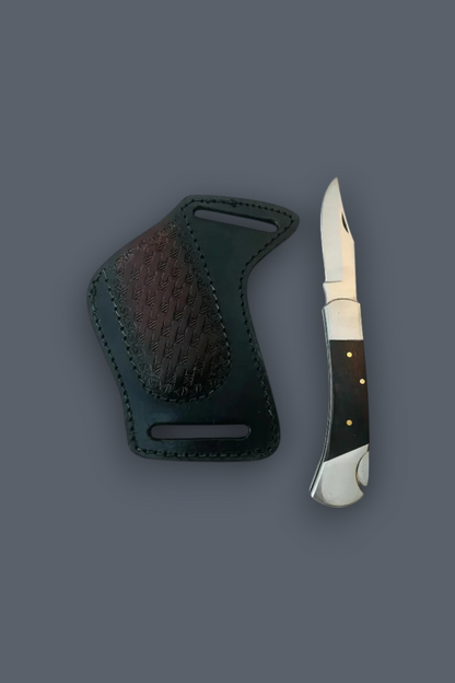 A compact folding pocket knife with sheath with a dark handle and silver blade, displayed next to its dark green leather sheath on a solid dark gray background.