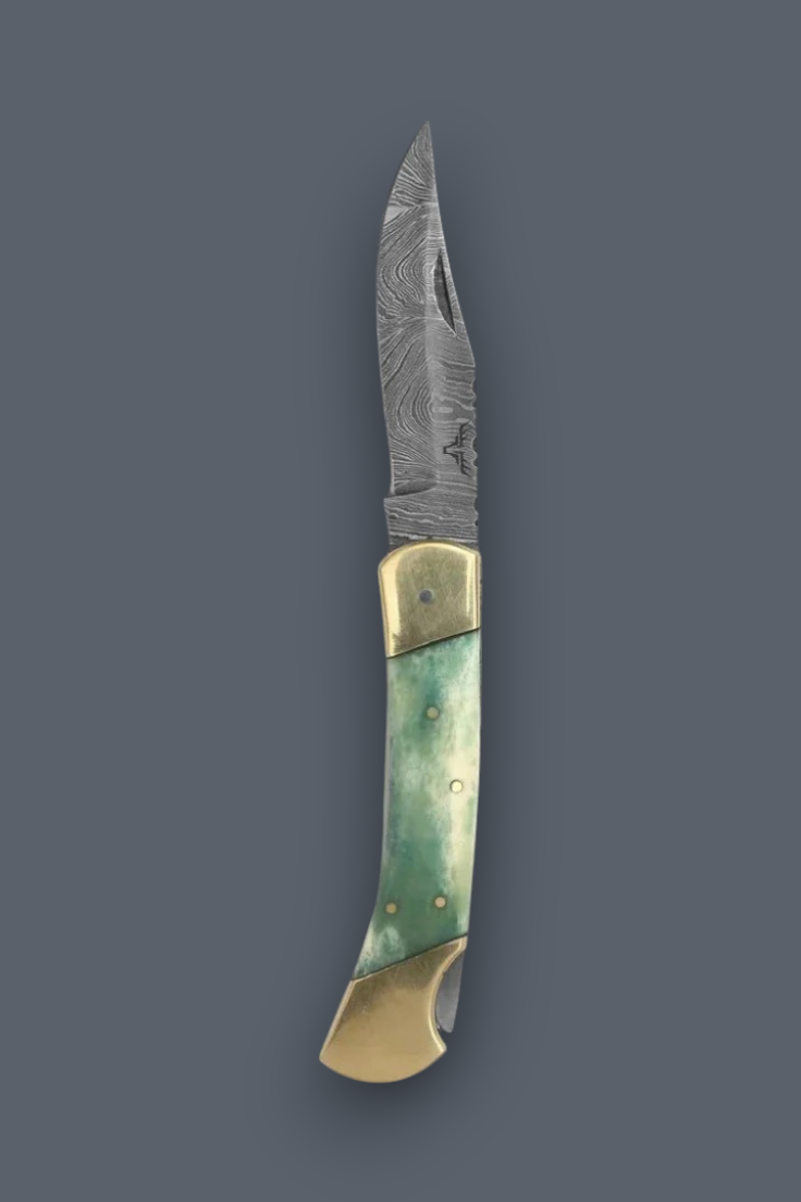 A folding pocket knife with a Damascus steel blade, brass bolsters, and a green bone handle, shown vertically on a dark gray background.