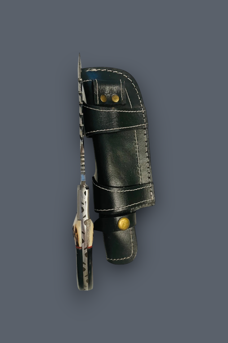 A fixed-blade knife with a patterned silver blade and a dark handle, sheathed in a black leather sheath with brass snaps, set against a solid dark gray background.