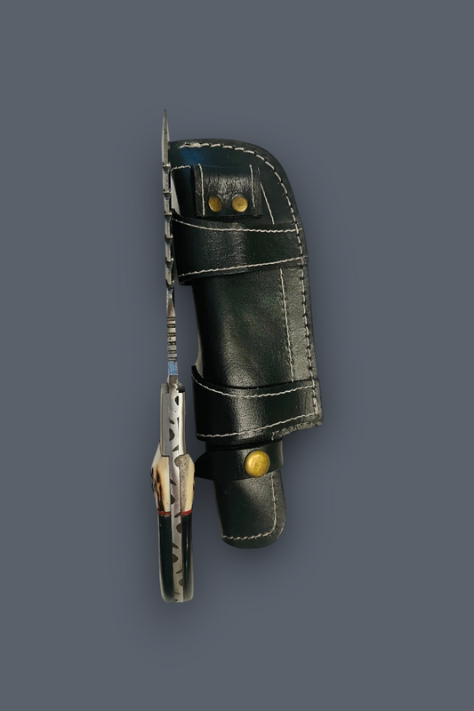 A fixed-blade knife with a patterned silver blade and a dark handle, sheathed in a black leather sheath with brass snaps, set against a solid dark gray background.