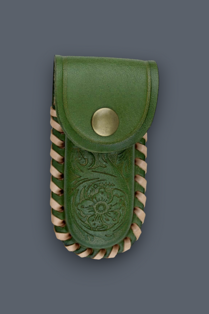 An olive green leather pouch with a snap button closure, featuring an embossed floral design on the front and twisted tan leather trim along the edges, set against a solid dark gray background.