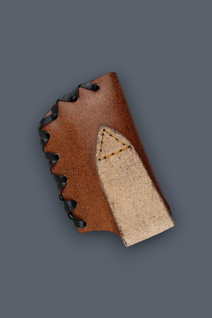 A close-up of a brown leather boot or shoe component with black laces and a light beige suede or leather insert, shown on a solid dark gray background.