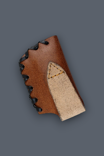 A close-up of a brown leather boot or shoe component with black laces and a light beige suede or leather insert, shown on a solid dark gray background.