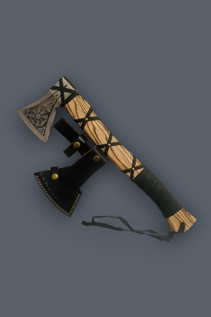 A decorative axe with a carved light wood handle wrapped in black leather, a black leather sheath, and a patterned metal head, shown on a solid dark gray background.