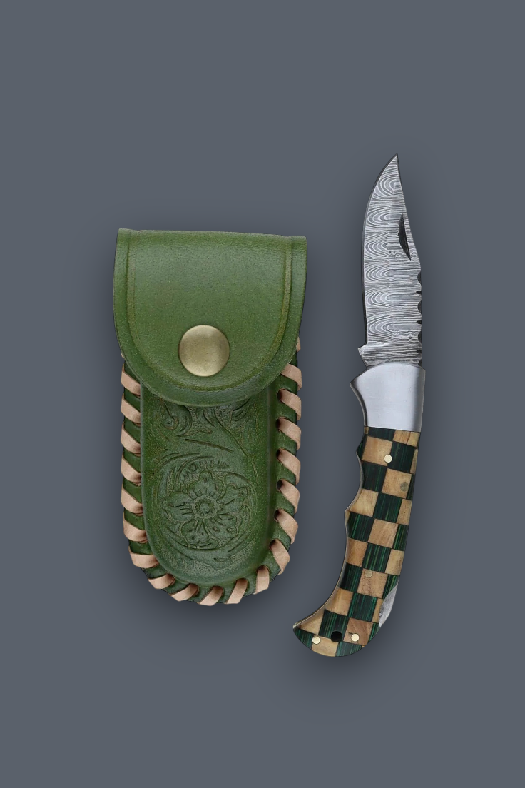 A folding pocket knife with a patterned steel blade and a green-and-tan checkered handle, shown next to its olive green leather sheath on a dark gray background.