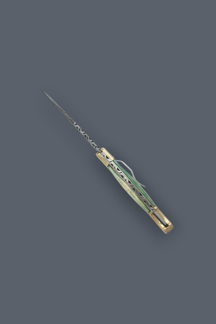 A folding pocket knife with a gold-toned metal handle and a long, thin silver blade, shown diagonally on a solid dark gray background.