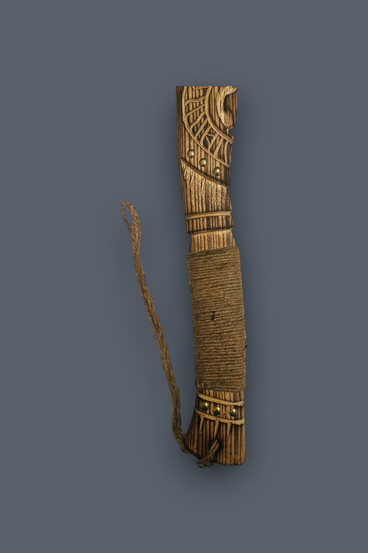 A carved wooden ceremonial or decorative object wrapped with brown cord, featuring geometric engravings and a hanging cord, shown against a solid dark gray background.
