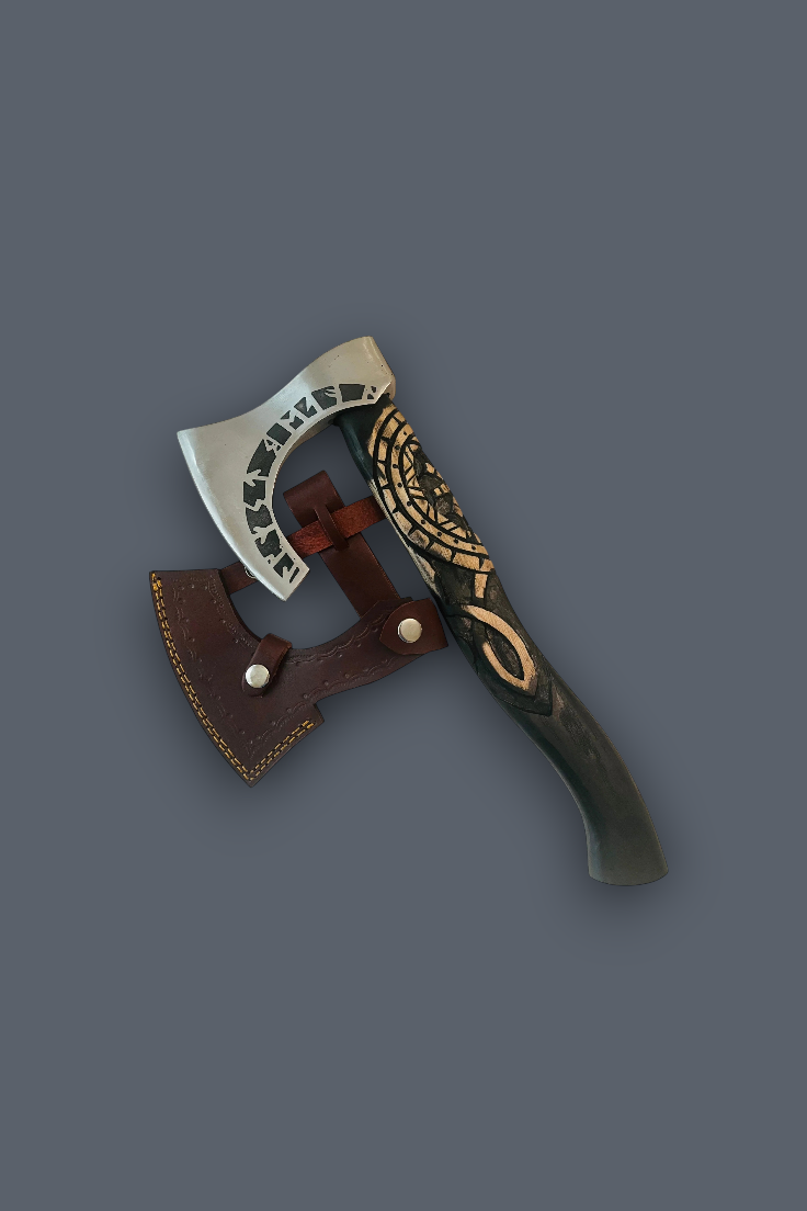 A decorative Viking-style hand axe with a silver blade, brown leather sheath, and ornate black and gold handle, shown on a solid dark gray background.