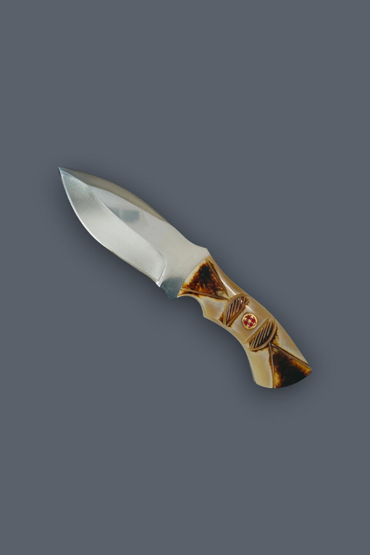 A fixed-blade knife with a polished silver steel blade and a decorative handle made of layered brown and beige wood, featuring a small red cross emblem, shown on a solid dark gray background.