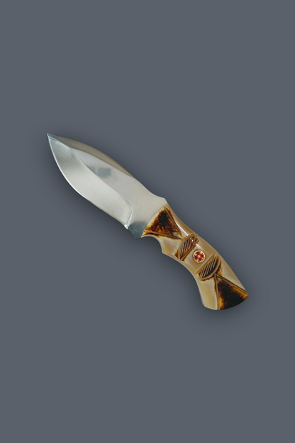 A fixed-blade knife with a polished silver steel blade and a decorative handle made of layered brown and beige wood, featuring a small red cross emblem, shown on a solid dark gray background.