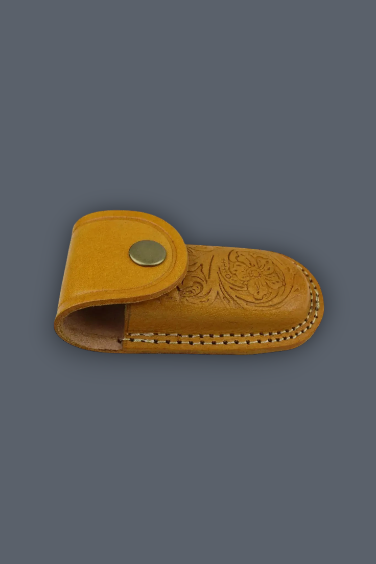 A small tan leather sheath with floral tooling on the main body, a snap closure tab, and visible stitching, shown on a plain dark gray background.