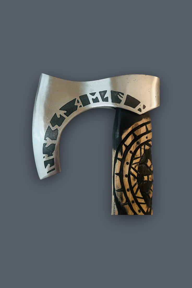 A Viking-style bearded axe with a silver-toned metal blade featuring runic engravings and a dark handle with a gold-toned circular pattern, shown against a solid dark gray background.
