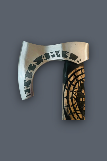 A Viking-style bearded axe with a silver-toned metal blade featuring runic engravings and a dark handle with a gold-toned circular pattern, shown against a solid dark gray background.