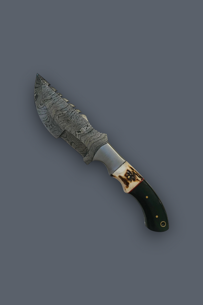 A decorative fixed-blade knife with a patterned steel blade, a silver bolster, and a dark green handle with gold accents, shown on a solid dark gray background.