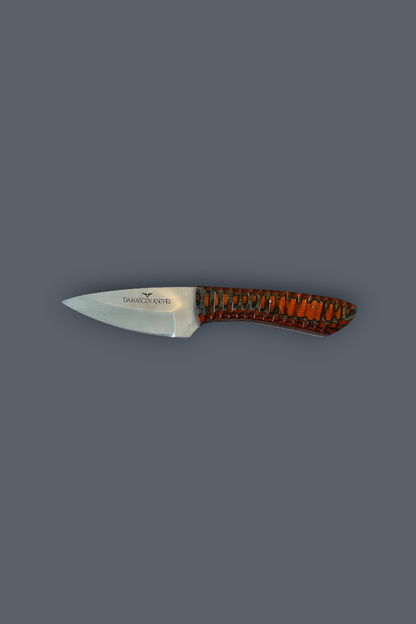 A small fixed-blade knife with a silver steel blade and a textured handle featuring a pattern of orange, brown, and black, shown against a solid dark gray background.