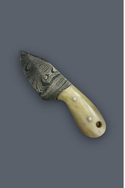 A small fixed-blade knife with a patterned Damascus-style steel blade and a cream-colored bone handle secured by three silver rivets, shown on a solid dark gray background.
