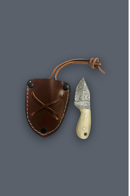 A small fixed-blade knife with a patterned steel blade and cream handle, shown next to its brown leather sheath on a solid dark gray background.