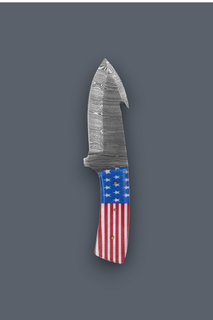 A fixed-blade knife with a patterned steel blade and a handle featuring an American flag design, shown against a solid dark gray background.