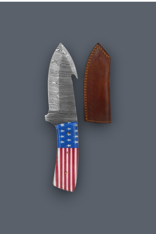 A fixed-blade knife with a patterned steel blade and an American flag handle, shown next to its brown leather sheath on a dark gray background.