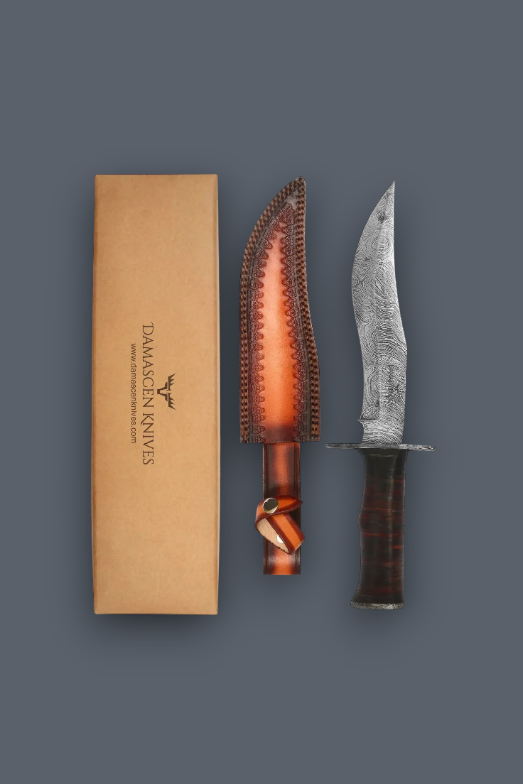 Damascus steel fixed blade knife shown next to its brown leather sheath and tan cardboard box on a dark gray background.