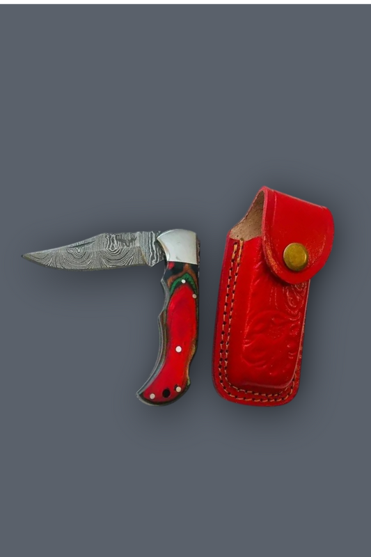 A folding pocket knife with a patterned steel blade and red handle, shown next to its red leather sheath on a solid dark gray background.