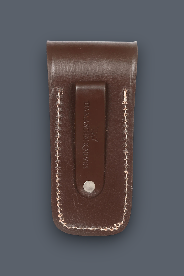 A brown leather knife sheath with white contrast stitching and a central leather tab stamped with the brand 'DALLAS BUCK', shown on a dark slate gray background.