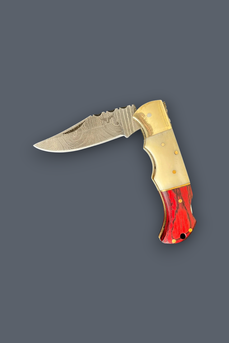 A folding pocket knife with a Damascus steel blade, gold-toned metal bolster, and a red and gold marbled handle, shown on a solid dark gray background.