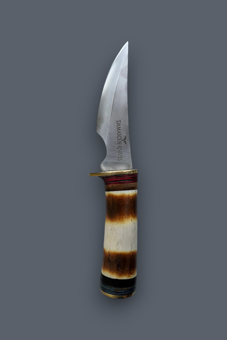 A fixed-blade knife with a curved silver steel blade and a natural horn handle showing brown and cream bands, set against a solid dark gray background.