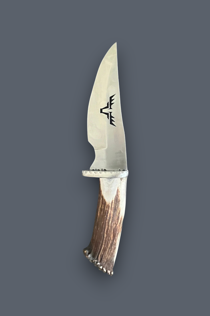 A fixed-blade knife with a polished silver steel blade featuring a black engraved logo, a silver bolster, and a natural brown antler handle, shown against a solid dark gray background.
