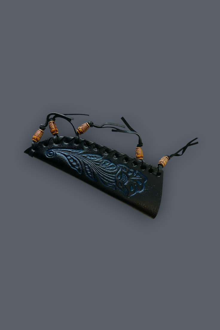 A black leather strap accessory with a carved blue-green floral design, featuring small brown wrapped beads on black cords, shown on a solid dark gray background.