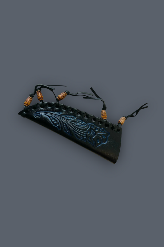 A black leather strap accessory with a carved blue-green floral design, featuring small brown wrapped beads on black cords, shown on a solid dark gray background.