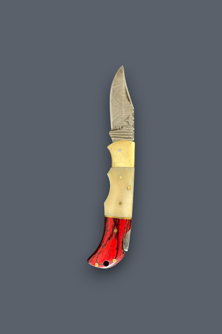 A folding pocket knife with a patterned steel blade, a cream-colored bone handle, and a red marbled resin end, shown vertically on a dark gray background.