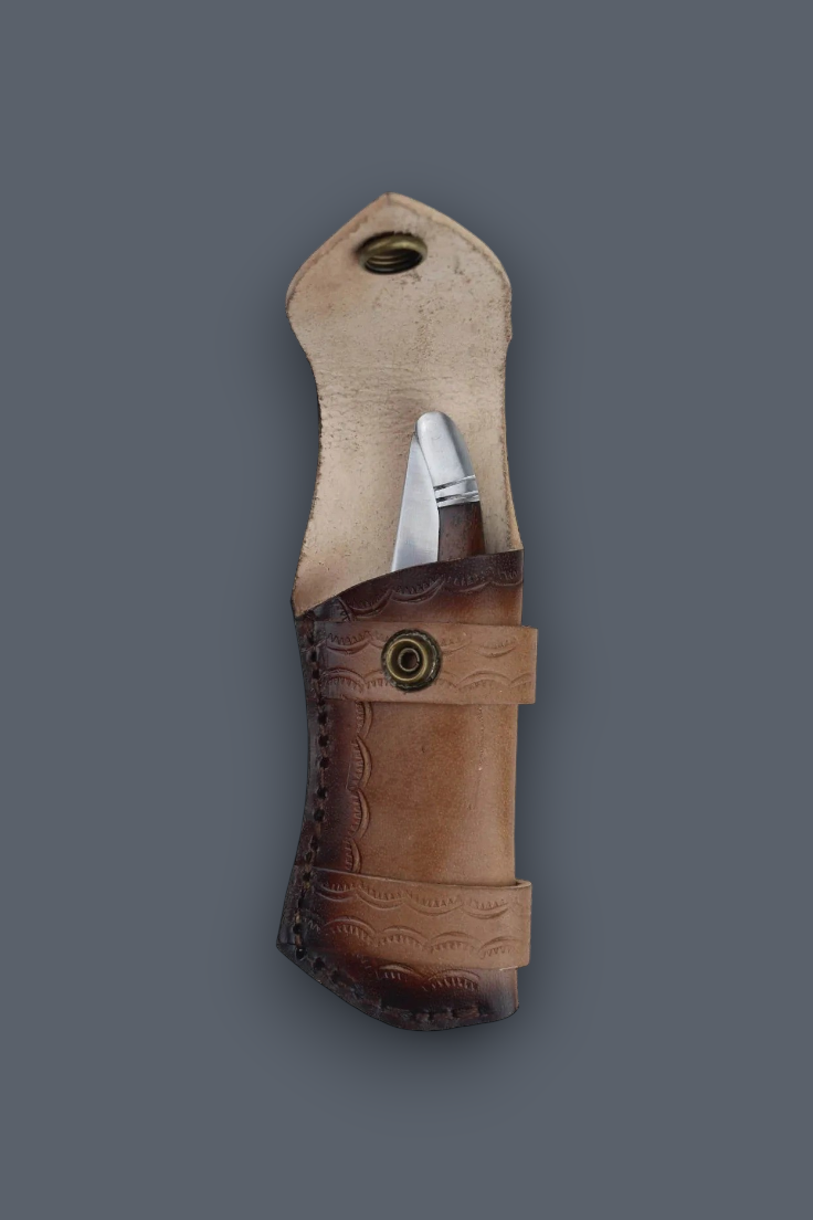 A leather knife sheath with a partially sheathed knife, shown against a solid dark gray background. The sheath features a light tan upper section and a darker brown lower section with embossed wave patterns and a snap button closure.