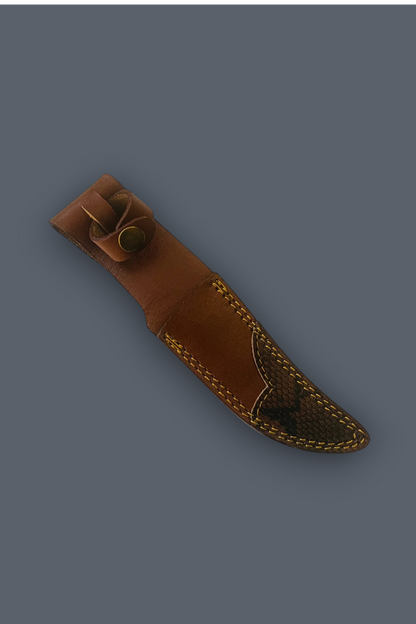 A brown leather knife sheath with decorative stitching and a brass snap button, shown diagonally on a solid dark gray background.