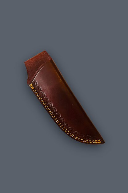 A brown leather knife sheath with decorative stamped patterns and gold-toned stitching, shown on a solid dark gray background.