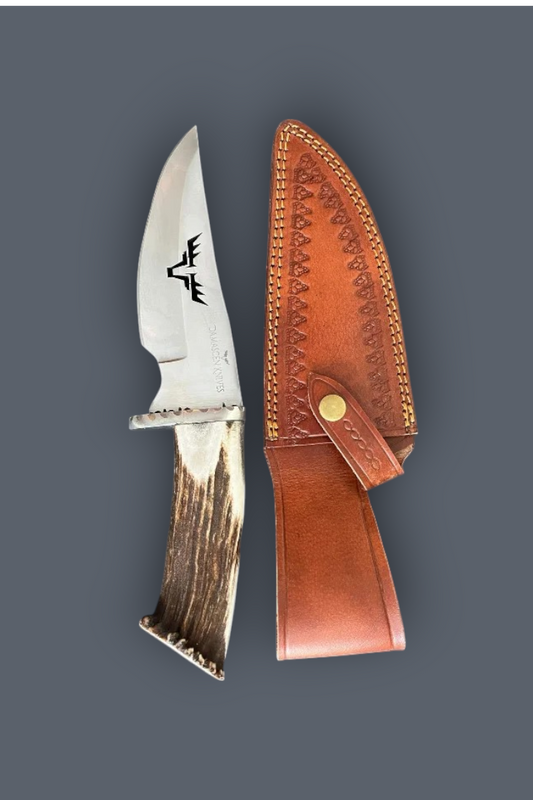 A fixed-blade knife with a silver blade featuring a black engraved logo, a natural antler handle, and a brown leather sheath, displayed on a solid dark gray background.