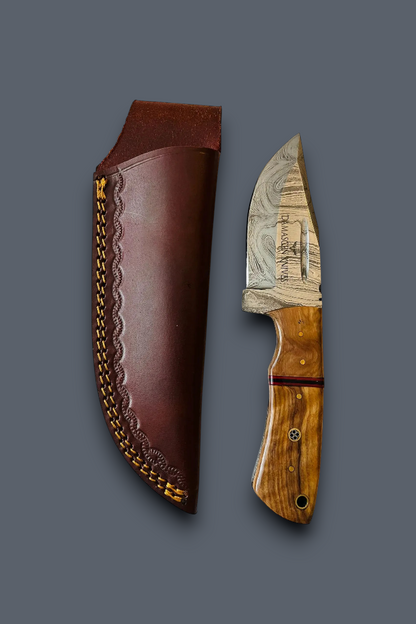 A fixed-blade knife with a patterned steel blade and a carved wood handle, displayed next to its brown leather sheath with gold-colored stitching on a dark gray background.
