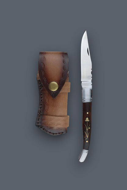 A folding pocket knife with a dark brown wooden handle and silver blade, displayed next to its brown leather sheath on a solid dark gray background.