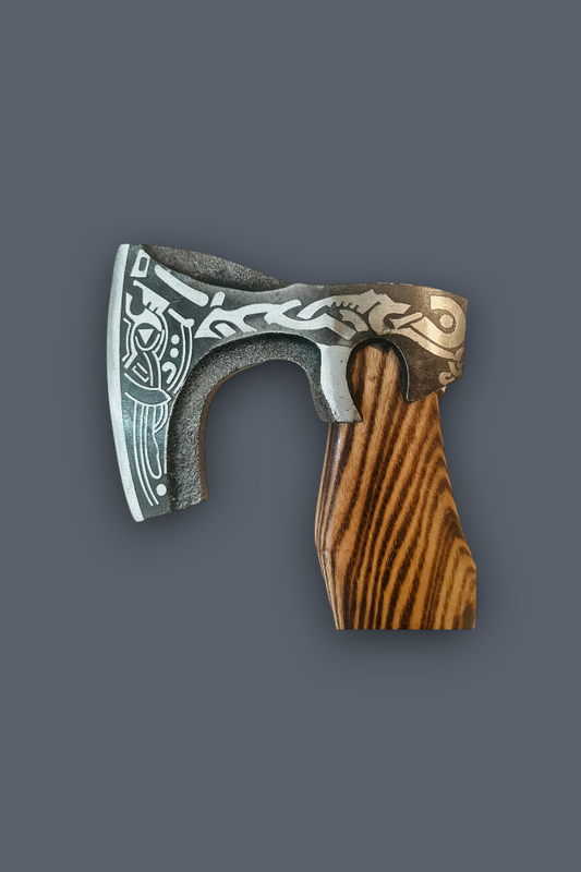 A decorative Viking-style axe with an engraved silver steel blade and a carved brown wooden handle, shown against a solid dark gray background.