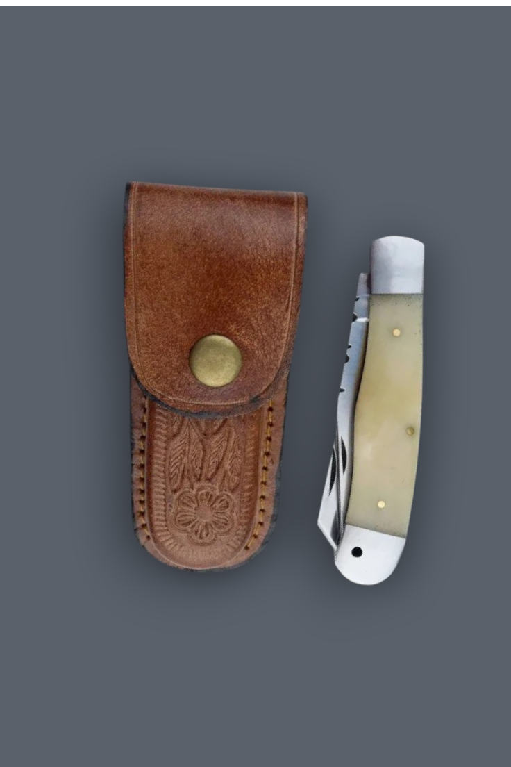 A folding pocket knife with a cream-colored bone handle and silver blade, displayed next to its brown leather sheath with an embossed eagle design and brass snap closure, set against a solid dark gray background.