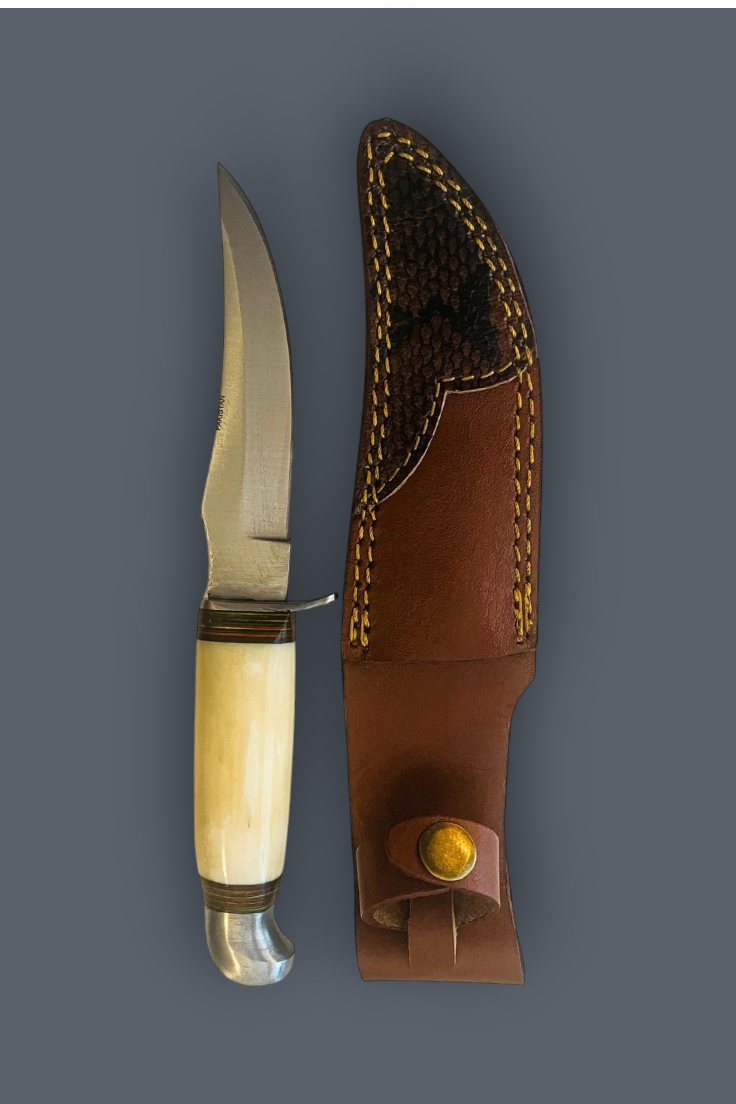 A fixed-blade knife with a curved cream-colored bone handle and a silver steel blade, displayed next to its brown leather sheath with yellow stitching on a solid dark gray background.