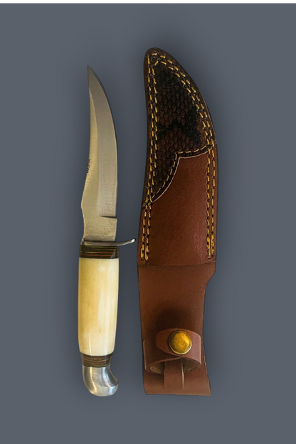 A fixed-blade knife with a curved cream-colored bone handle and a silver steel blade, displayed next to its brown leather sheath with yellow stitching on a solid dark gray background.